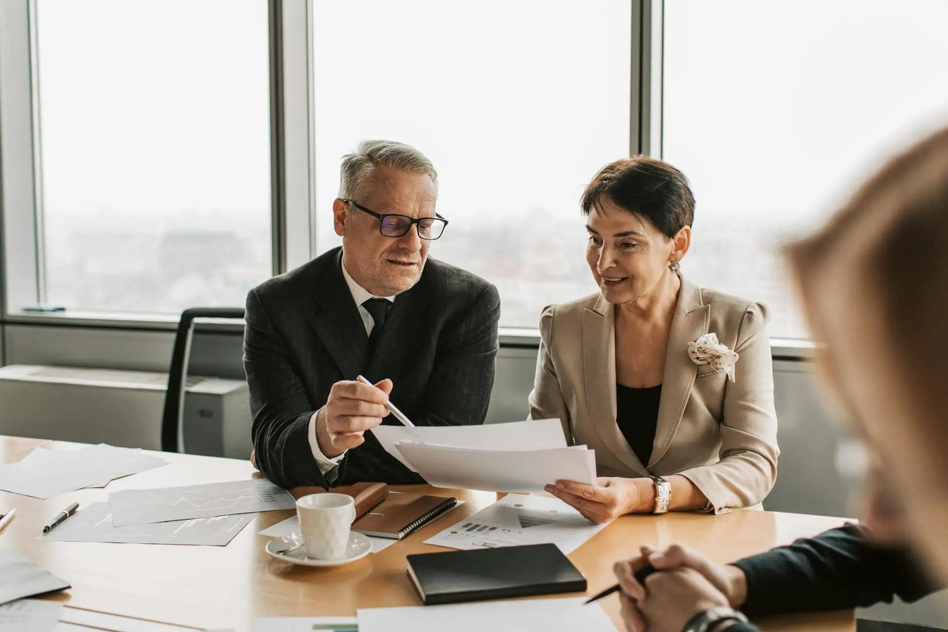 Two business professionals discussing documents during a formal meeting in office.